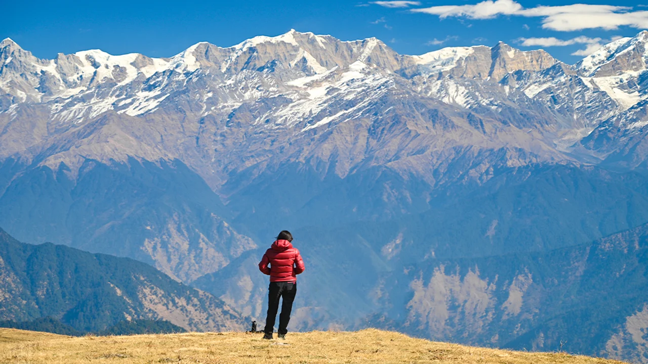 Trekker is enjoying the panoramic view of the mountains on the Dayara Bugyal Trek